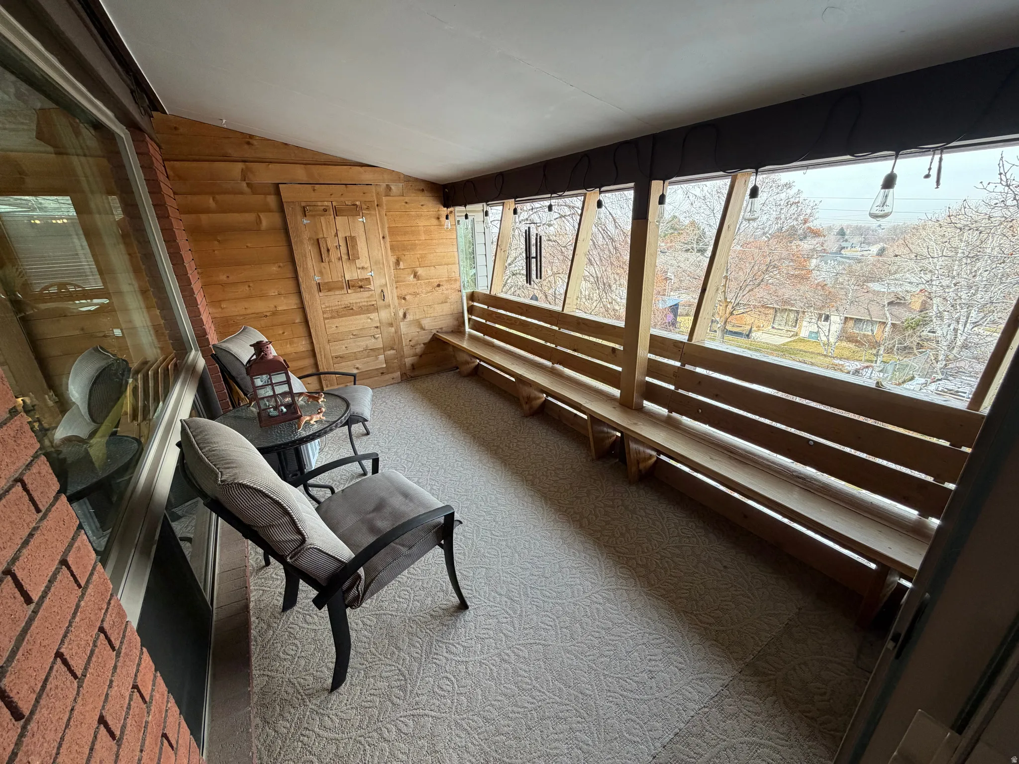 Sunroom featuring vaulted ceiling, carpet flooring, and wooden walls