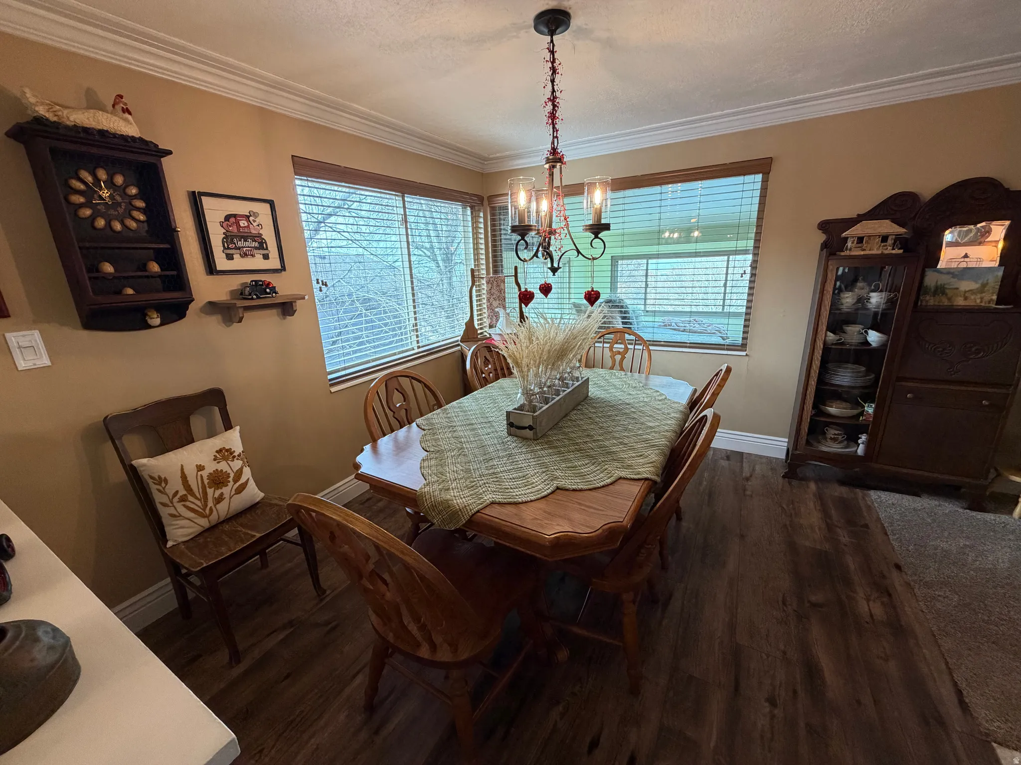 Dining space featuring dark wood-style flooring, a chandelier, crown molding, and a textured ceiling