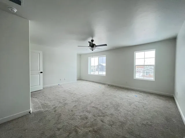 Carpeted spare room with ceiling fan and a smoke detector