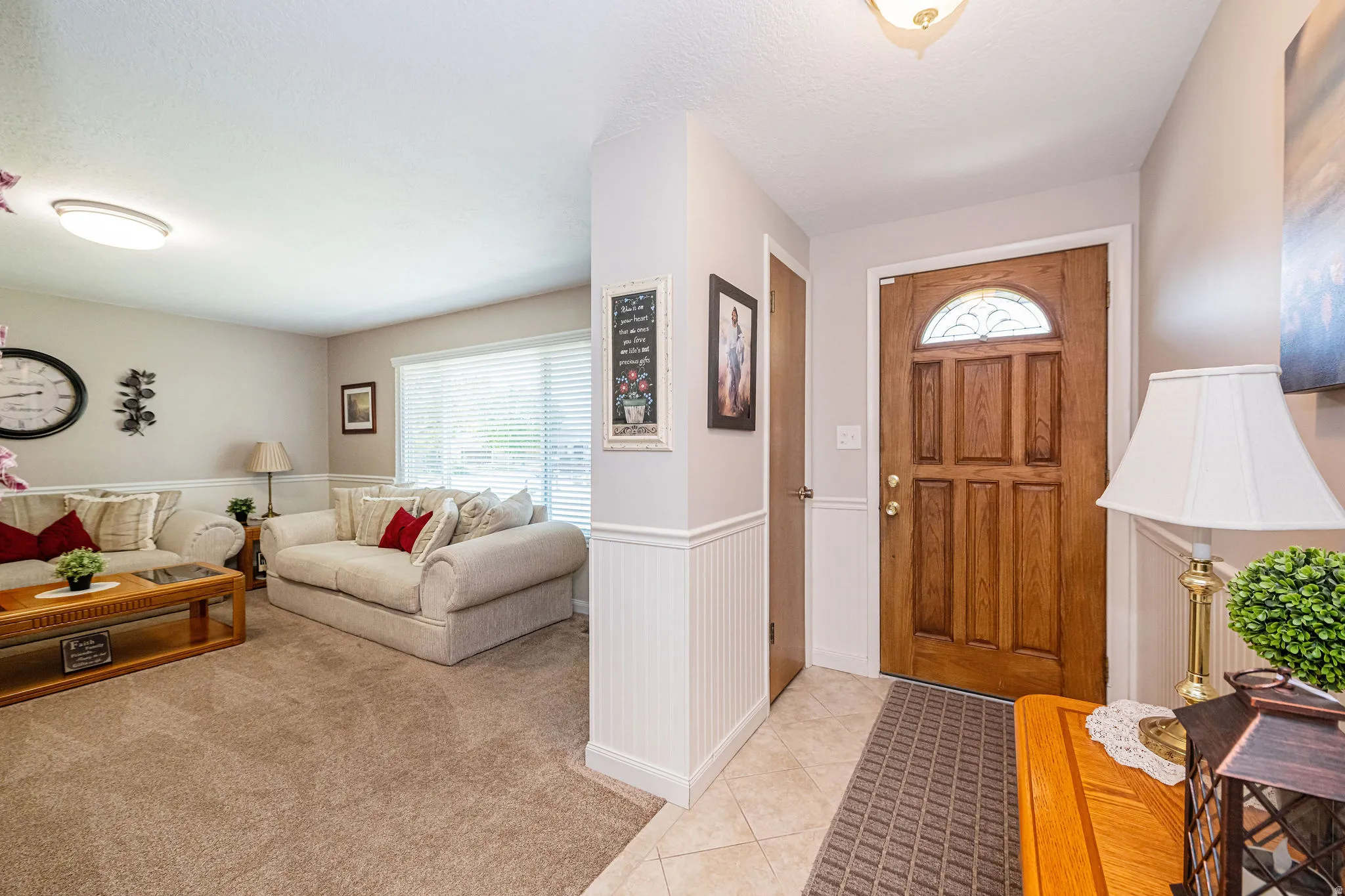 Entryway featuring a wainscoted wall, light tile patterned floors, and light colored carpet