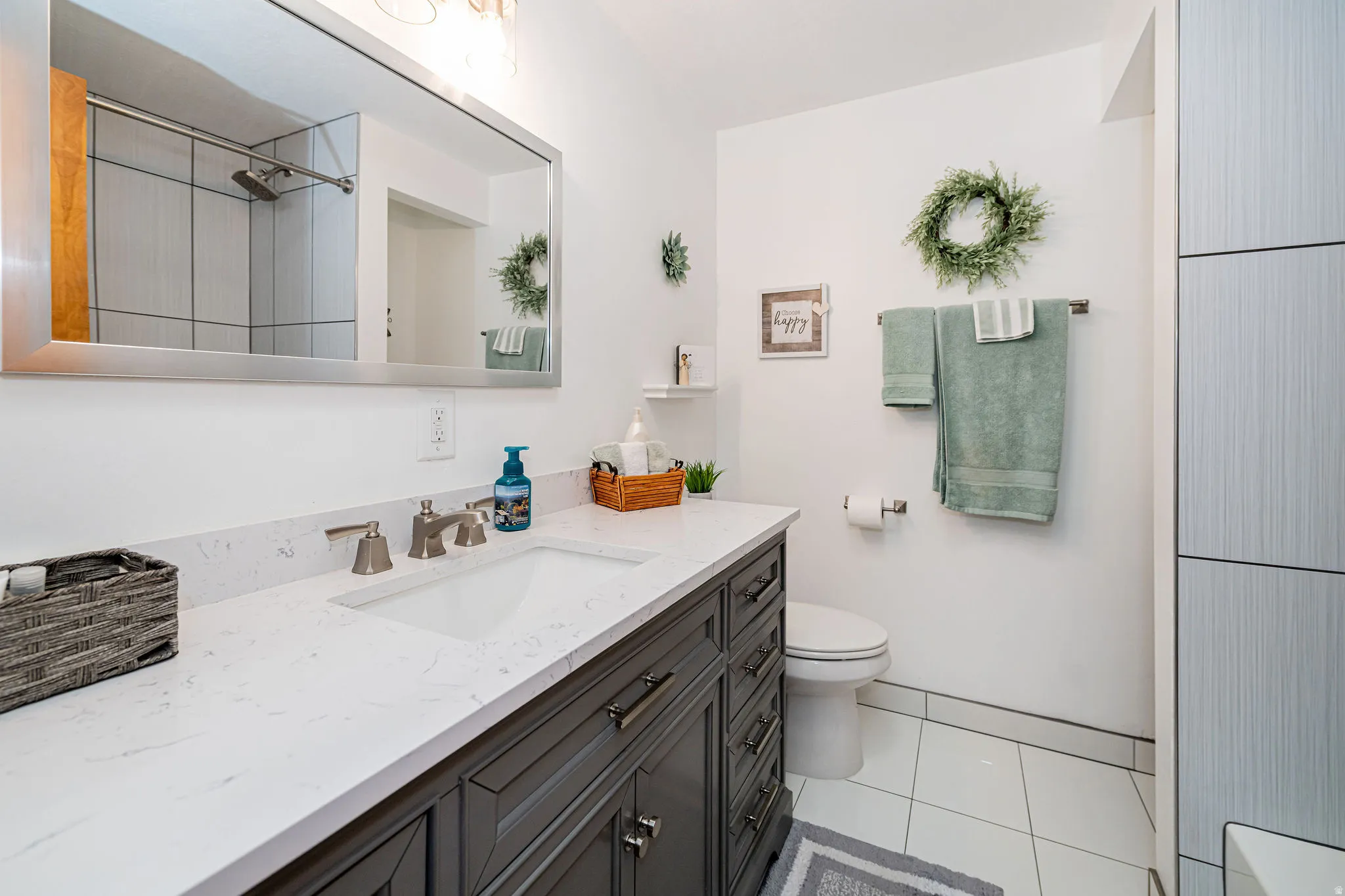 Bathroom with vanity, light tile patterned flooring, and a shower