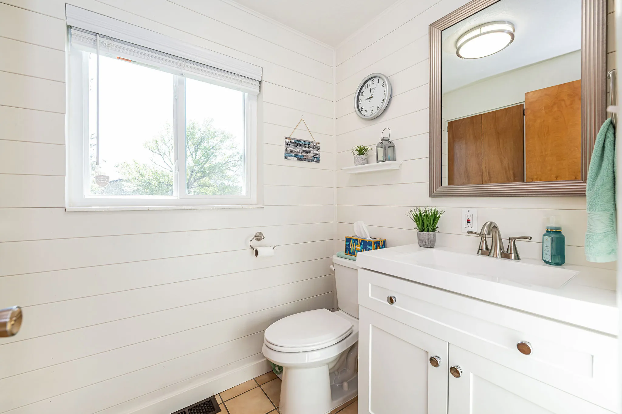Bathroom featuring vanity, wood walls, and light tile patterned flooring