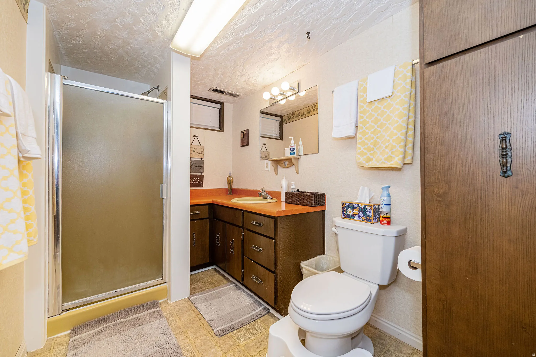 Bathroom with a stall shower, vanity, light floors, and a textured ceiling