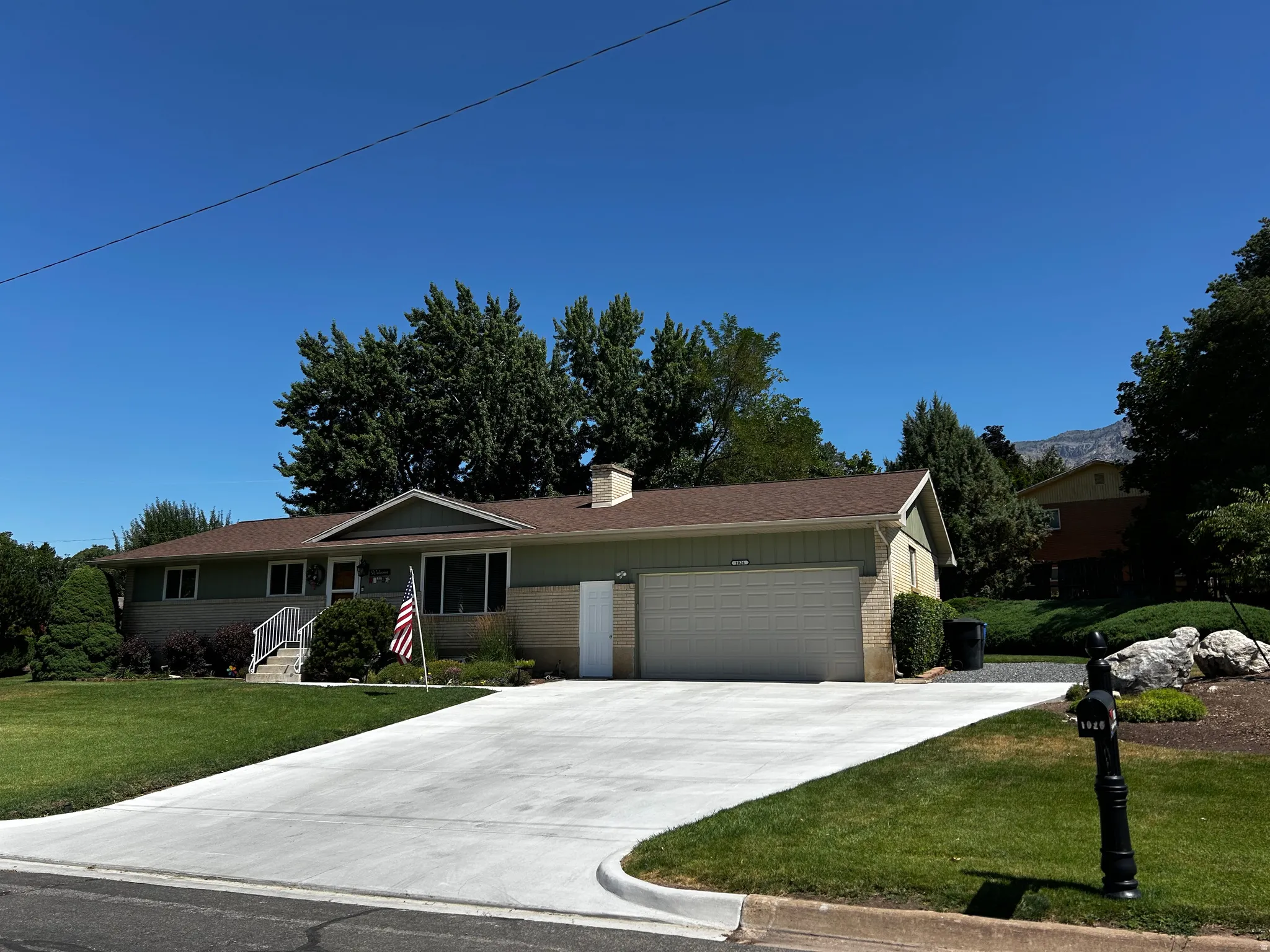Ranch-style home with brick siding, a front yard, an attached garage, concrete driveway, and a chimney
