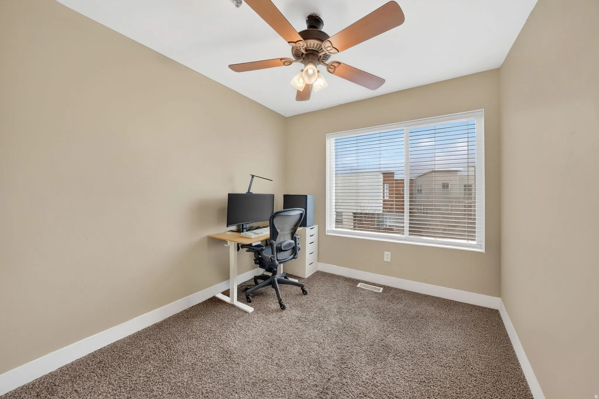 Carpeted office with baseboards and a ceiling fan
