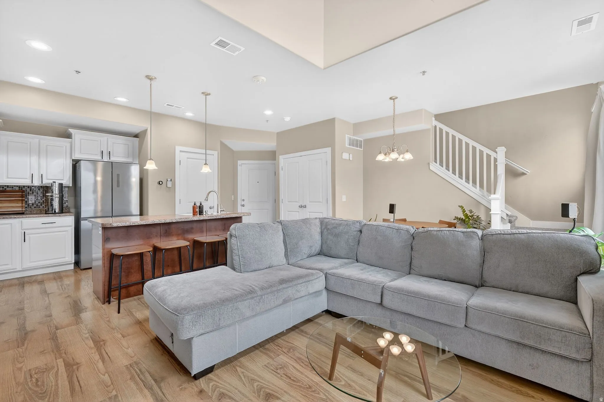 Living room featuring stairs, light wood finished floors, and a chandelier