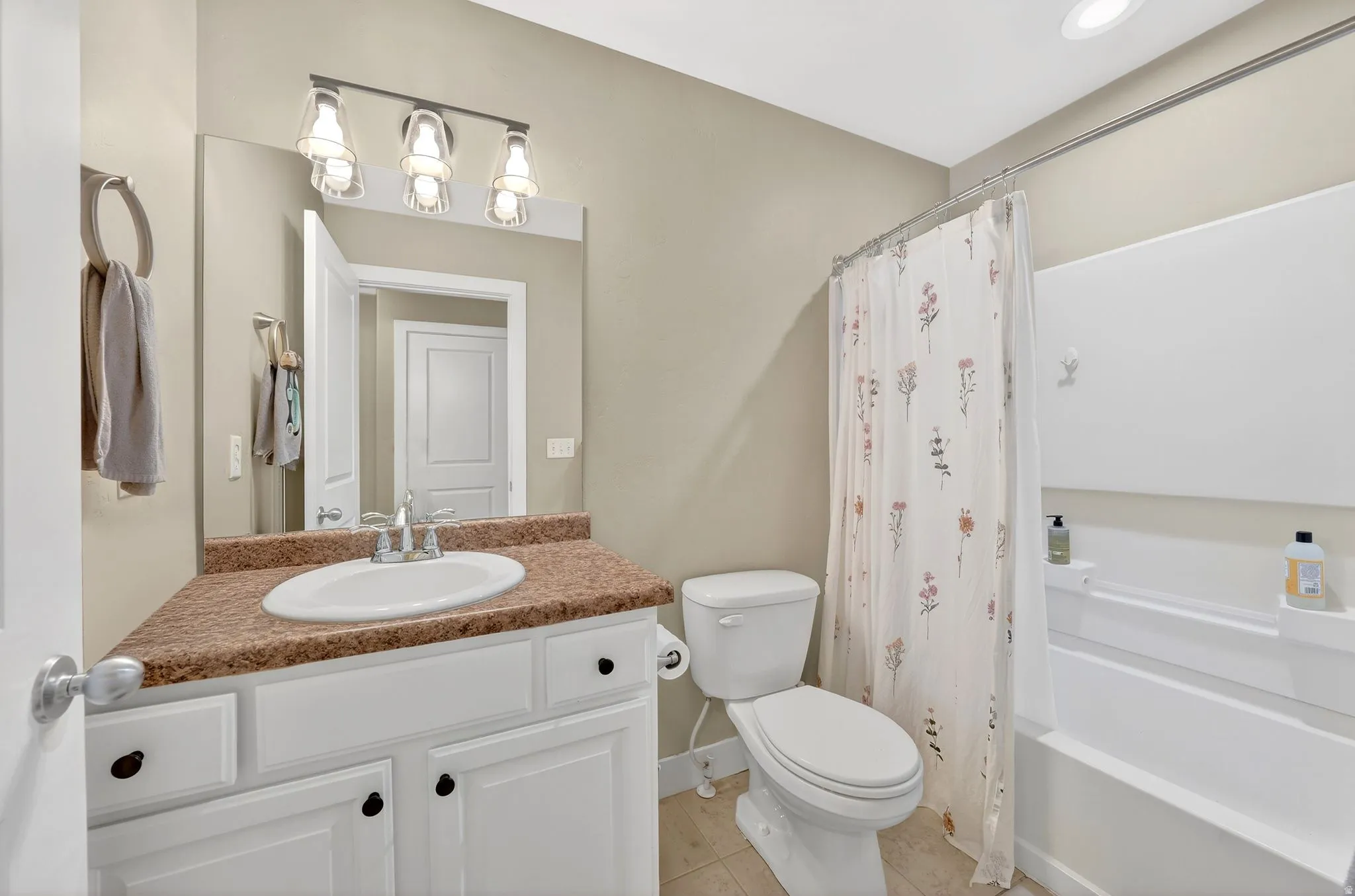 Full bathroom featuring vanity, shower / bath combination with curtain, and light tile patterned floors