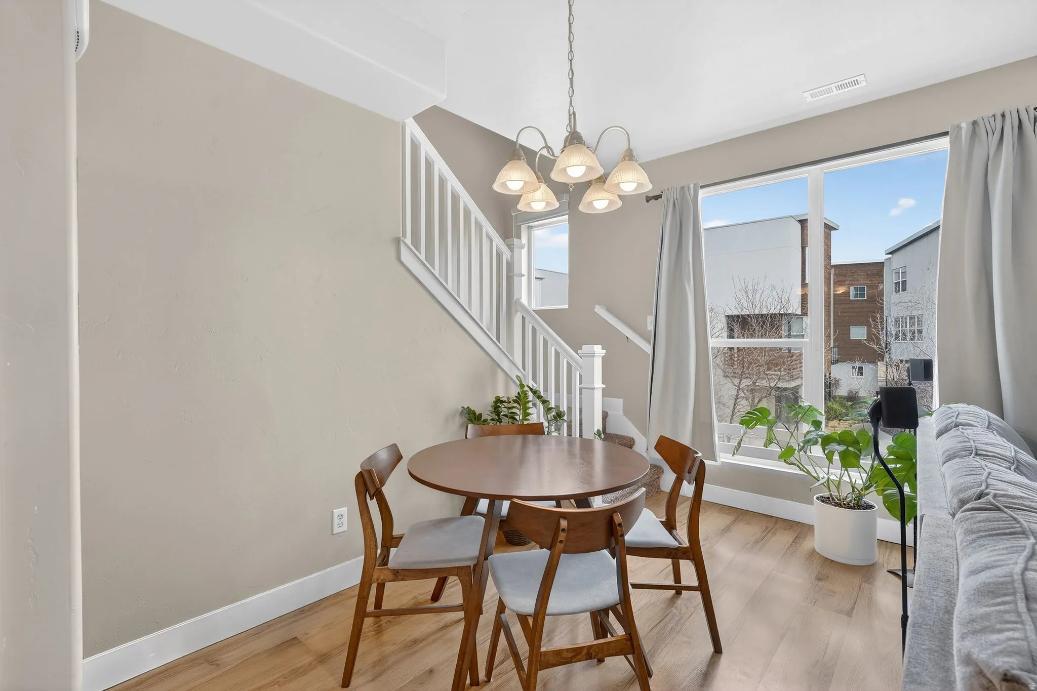 Dining area with wood finished floors, stairway, and a chandelier