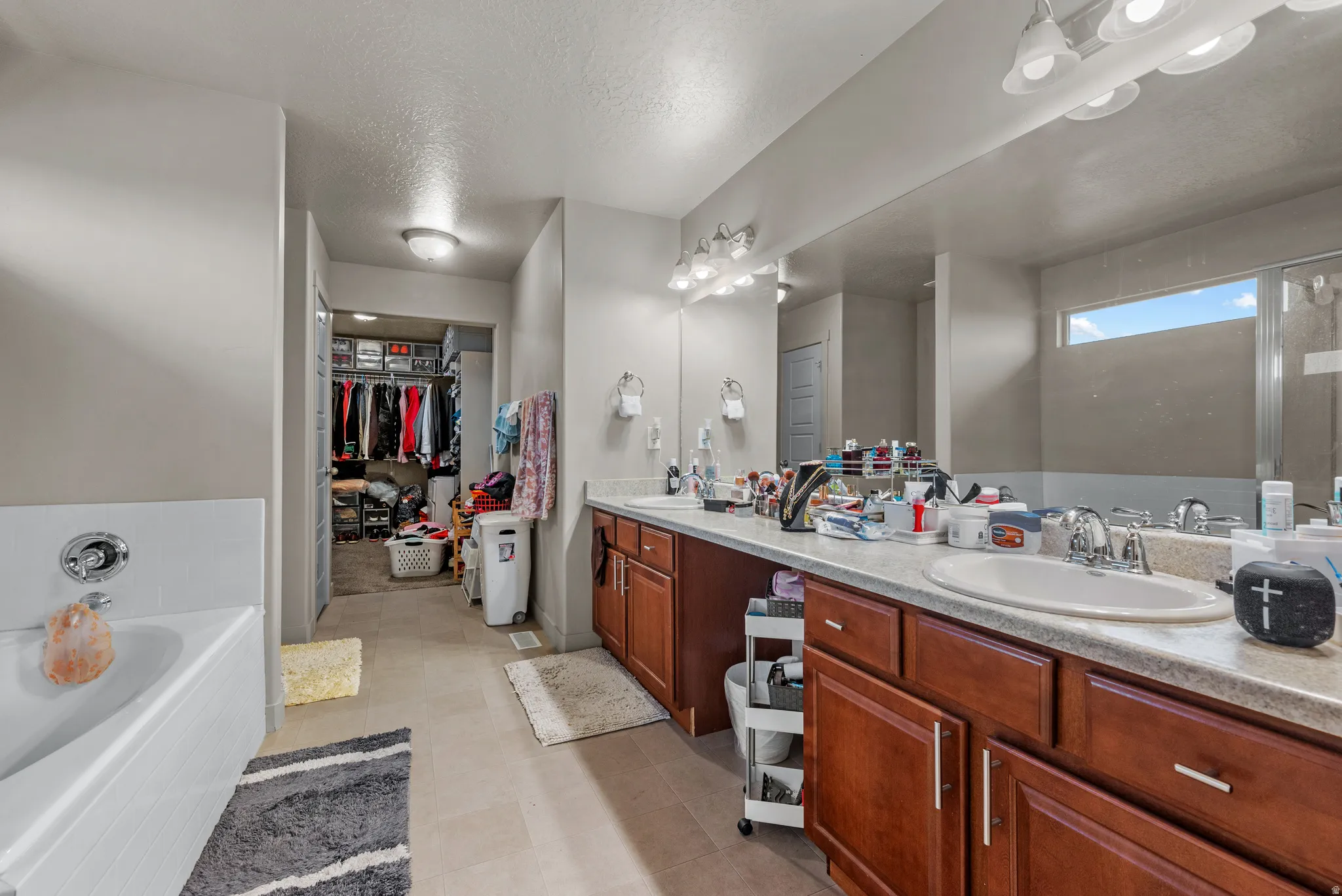 Full bathroom with a spacious closet, double vanity, a garden tub, a textured ceiling, and an enclosed shower