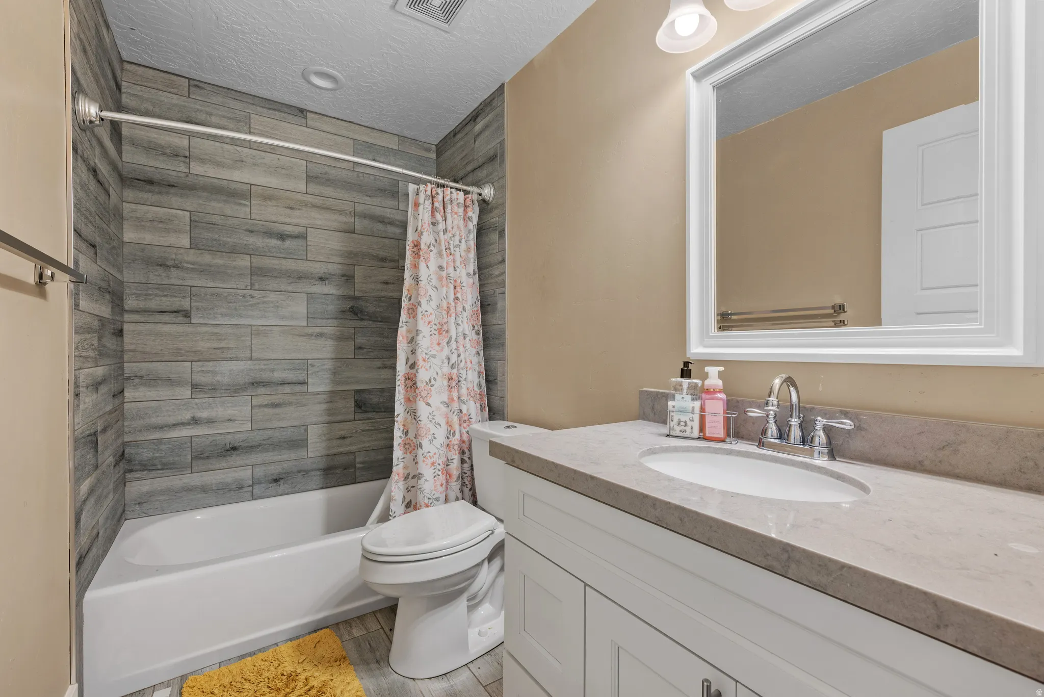 Full bathroom featuring shower / tub combo with curtain, vanity, a textured ceiling, and light wood-style flooring