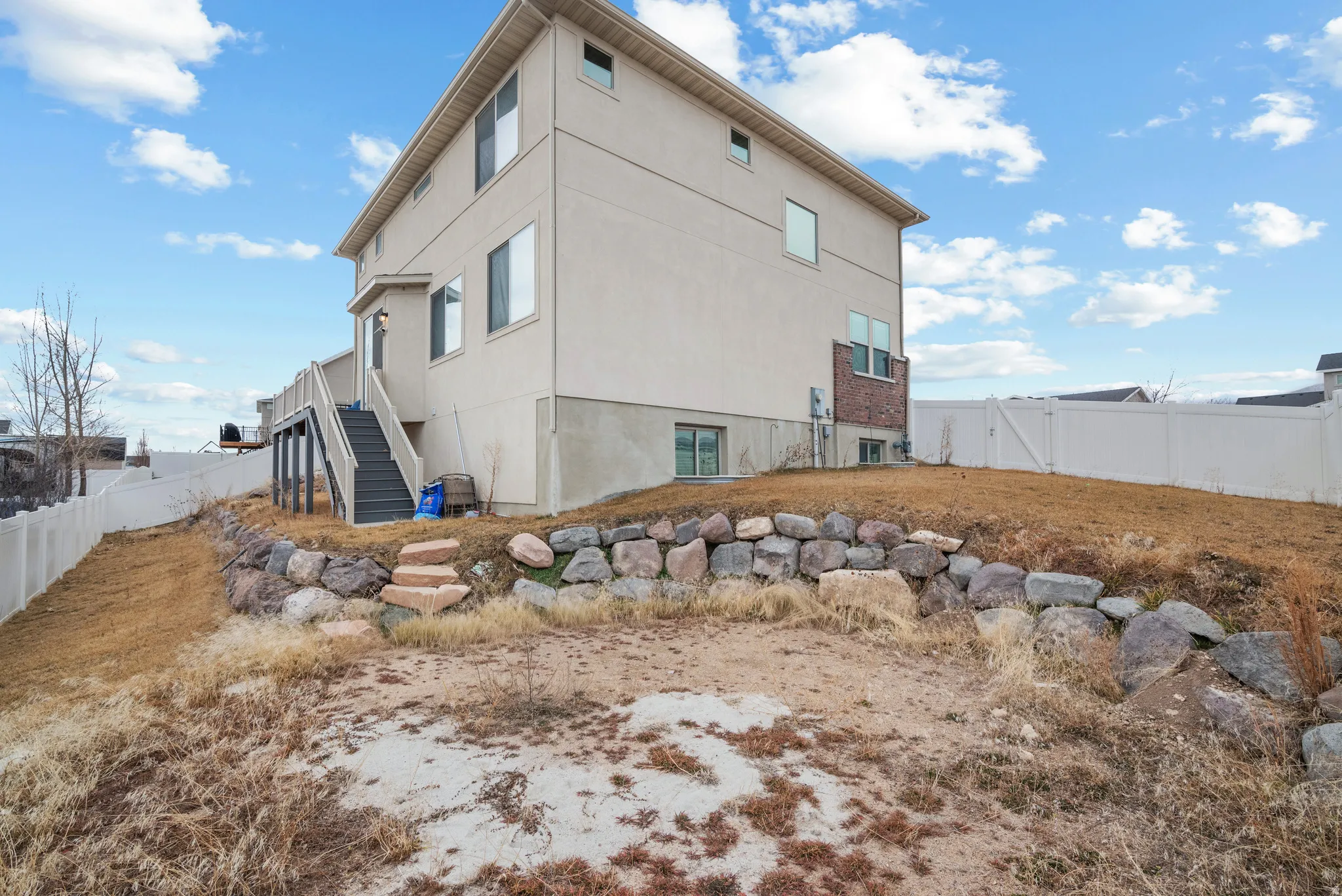 View of side of property with a fenced backyard and stucco siding