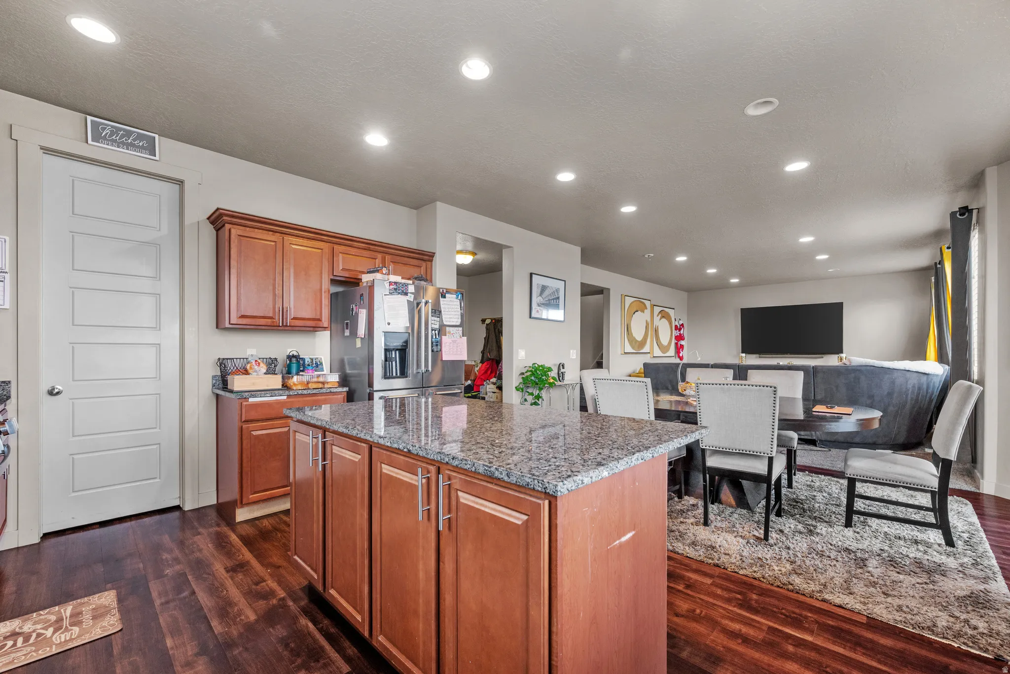 Kitchen with wood finish cabinetry, dark stone countertops, a kitchen island, dark wood-style floors, and recessed lighting