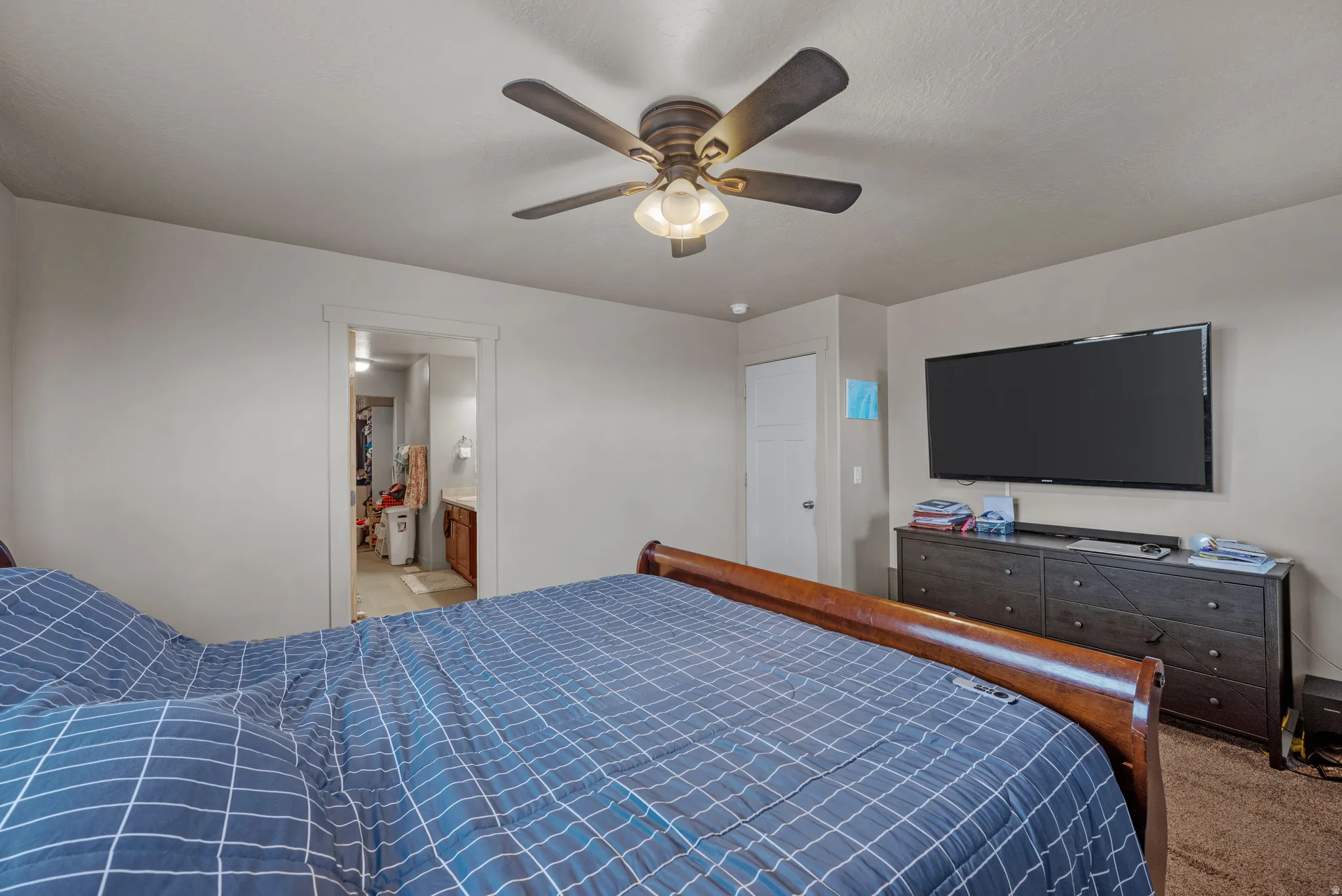 Bedroom featuring light colored carpet, ceiling fan, and ensuite bath