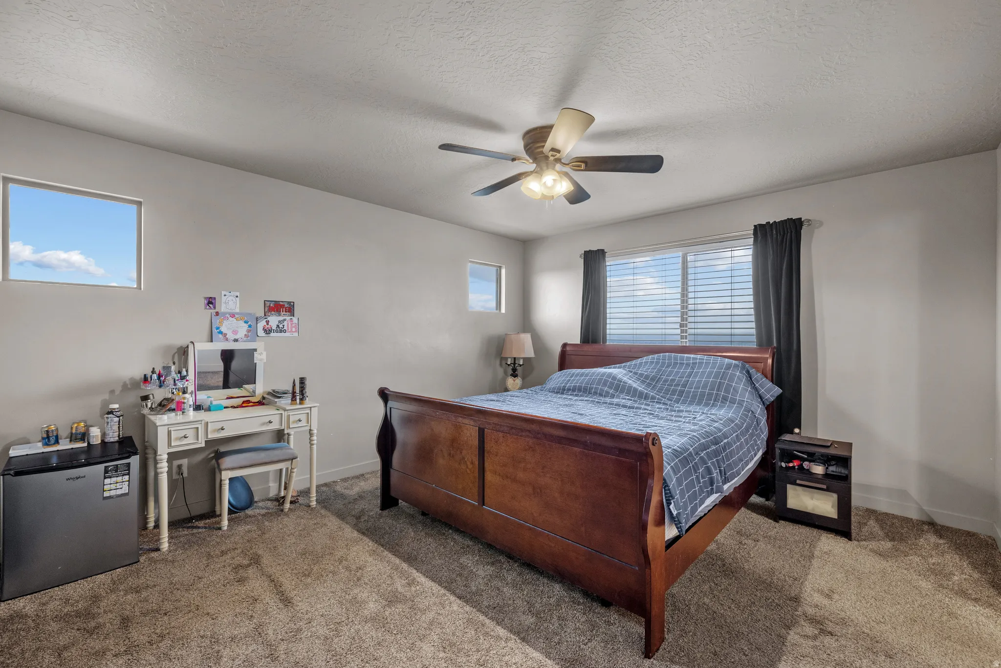 Bedroom featuring stainless steel fridge, carpet, a textured ceiling, and ceiling fan