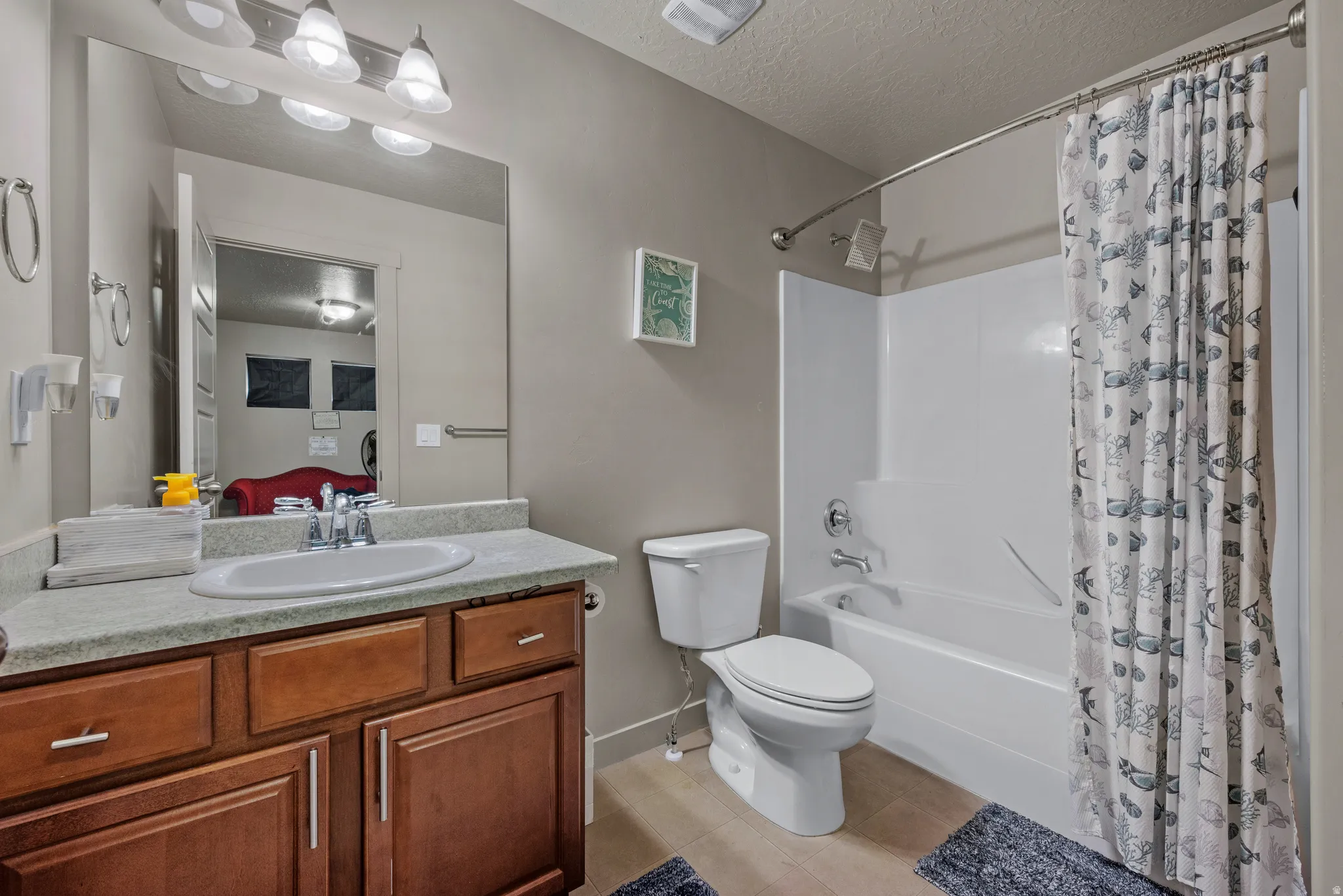 Bathroom with shower / bathtub combination with curtain, a textured ceiling, vanity, and light tile patterned floors