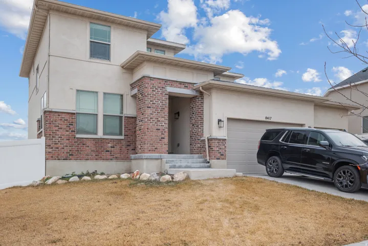 Prairie-style home featuring brick siding, stucco siding, and an attached garage