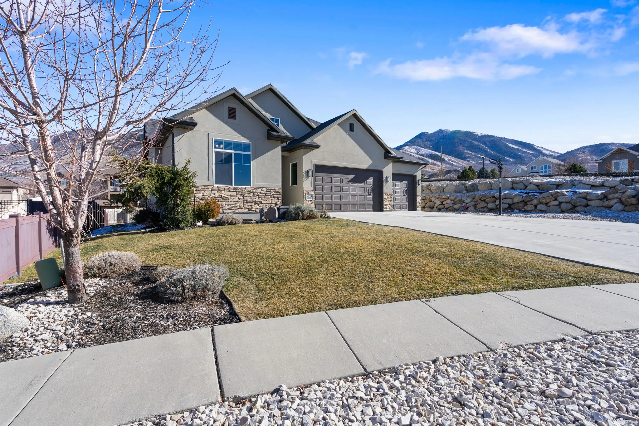View of front of home featuring stucco siding, stone siding, driveway, a mountain view, and a garage