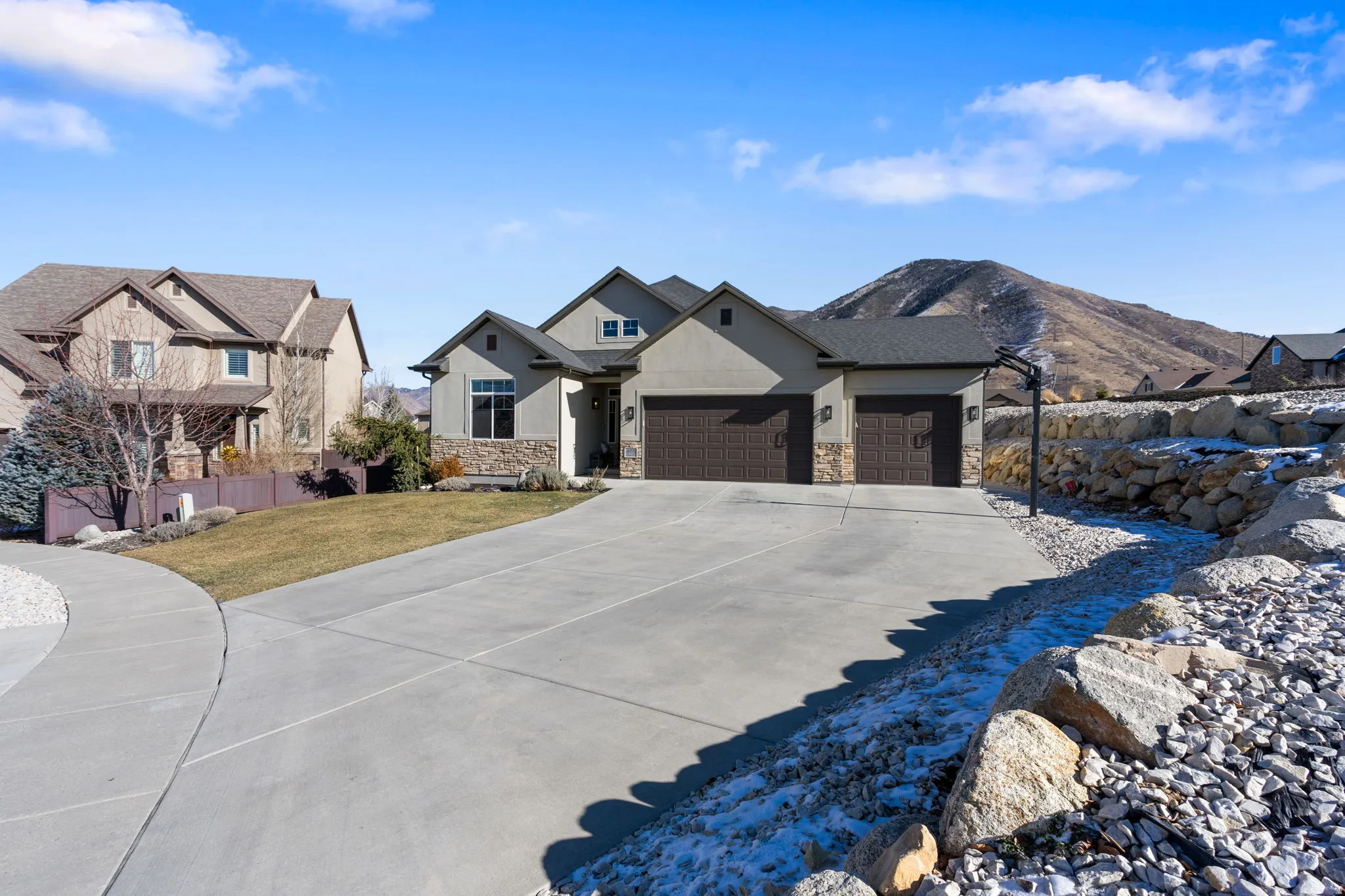 View of front of property with an attached garage, concrete driveway, stone siding, a front yard, and stucco siding