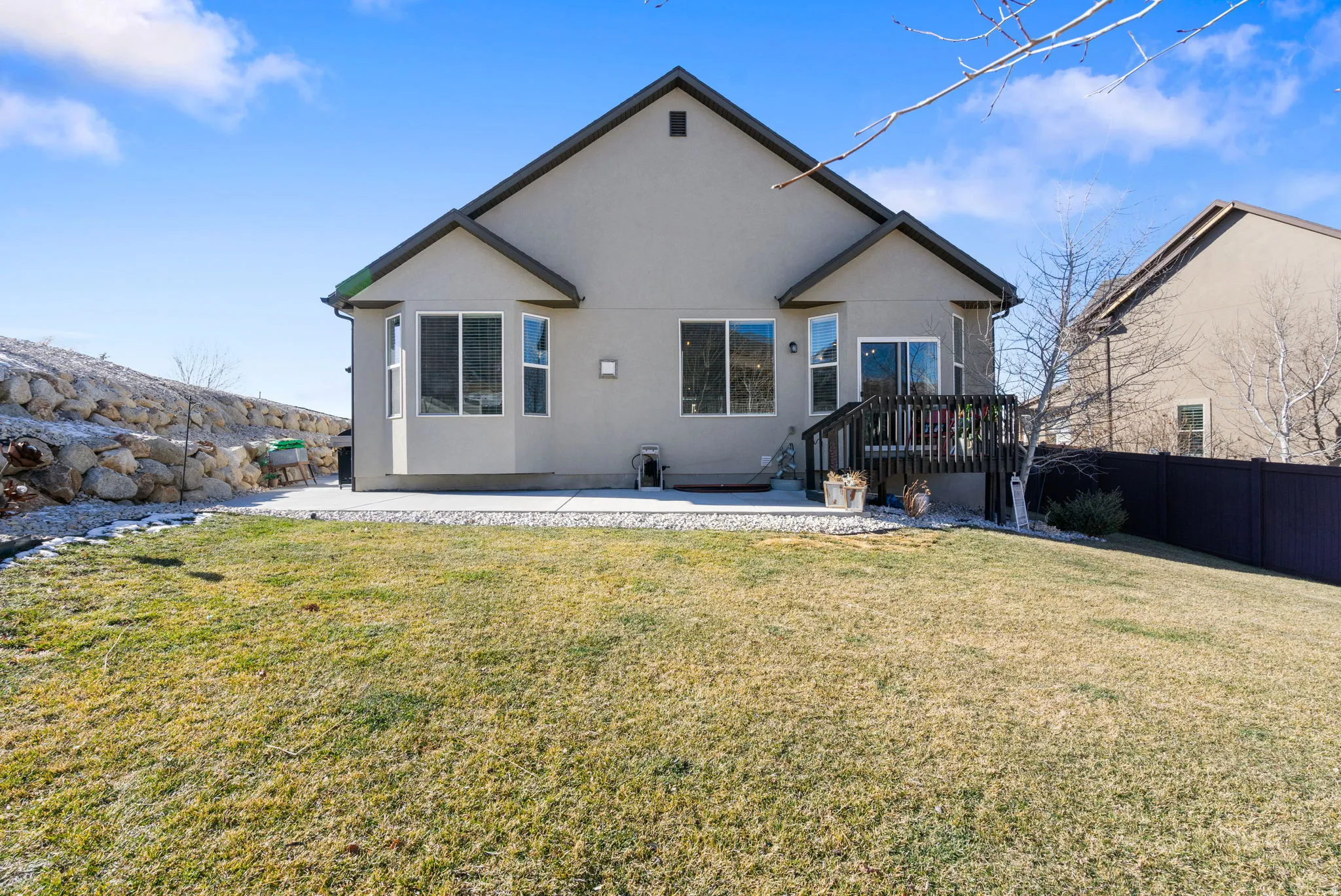Rear view of house with stucco siding, a patio area, and a wooden deck