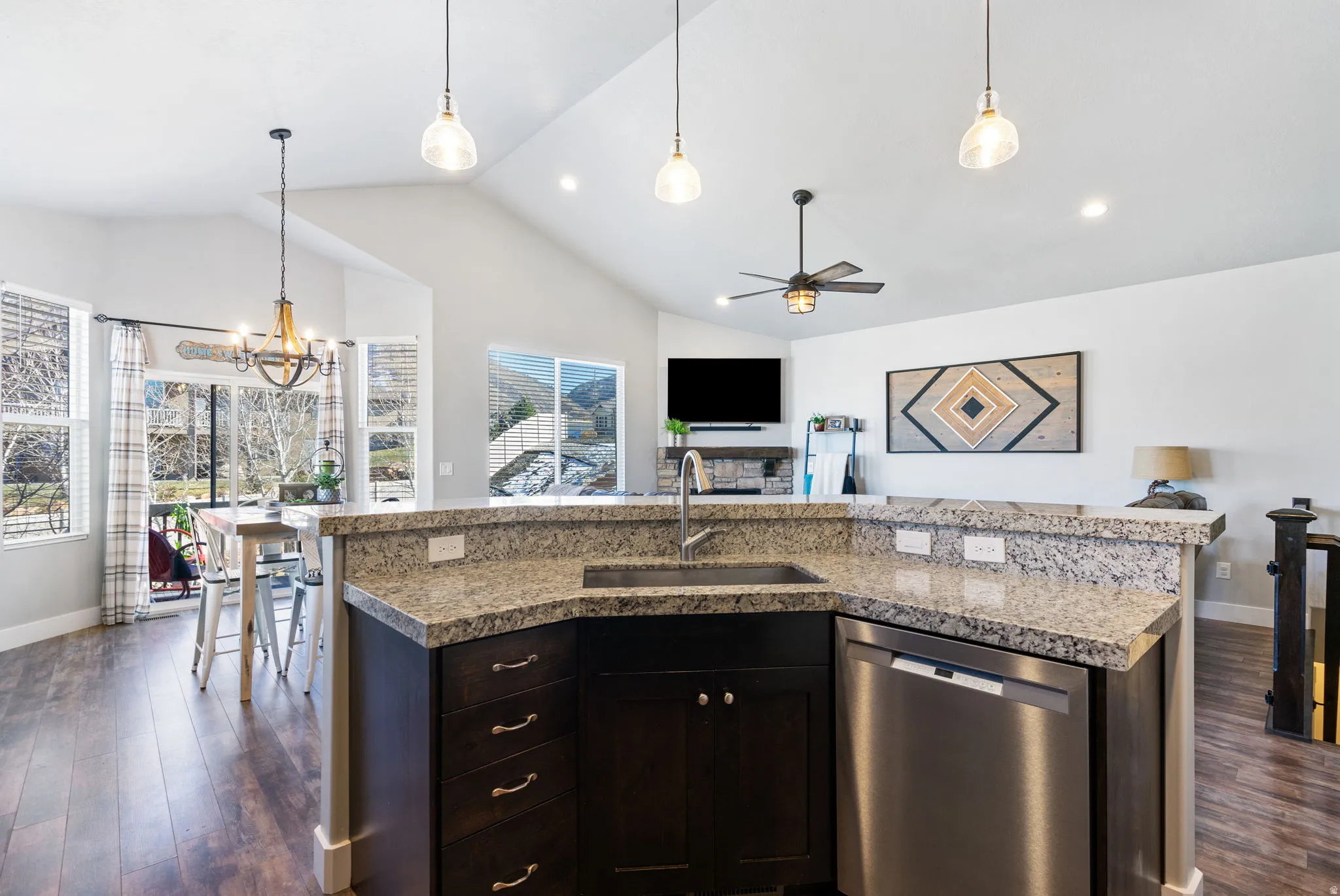 Kitchen featuring stainless steel dishwasher, pendant lighting, dark wood finished floors, a kitchen island with sink, and open floor plan