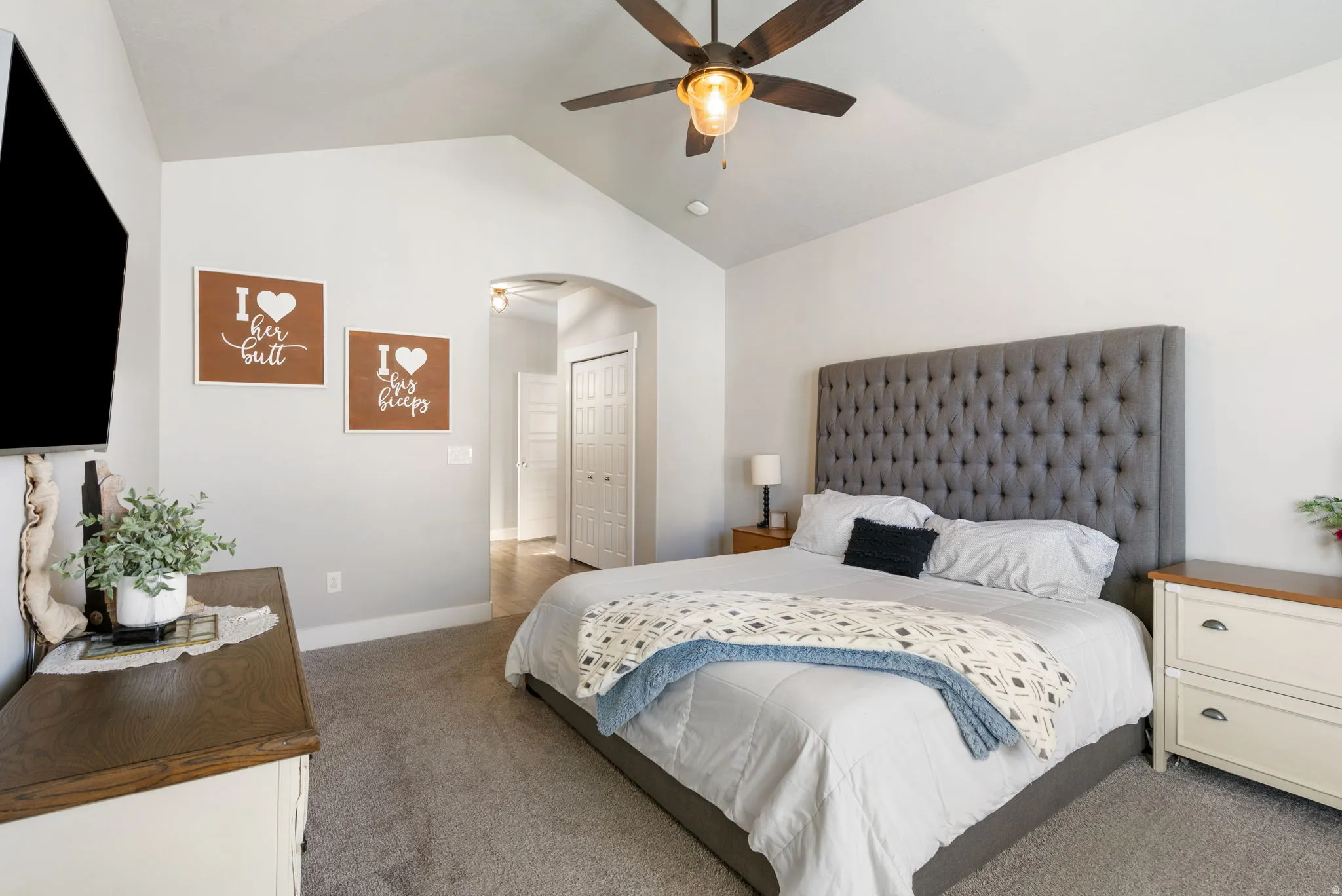 Carpeted bedroom featuring lofted ceiling, ceiling fan, and arched walkways