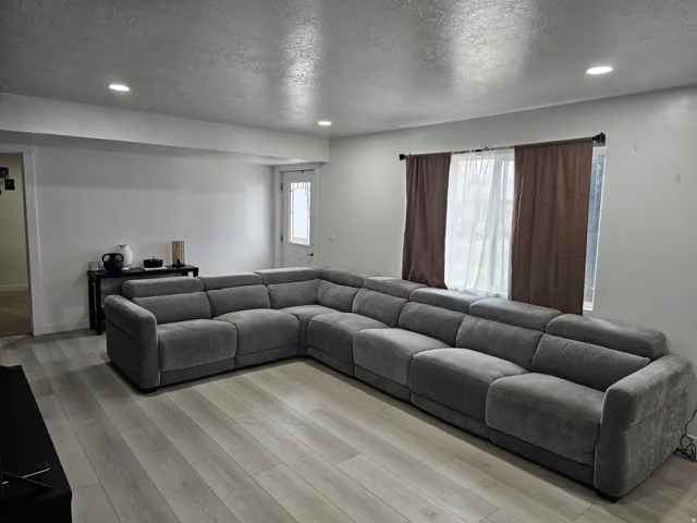 Living room with recessed lighting, a textured ceiling, and light wood-style floors