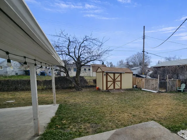 Fenced backyard featuring a shed and a patio