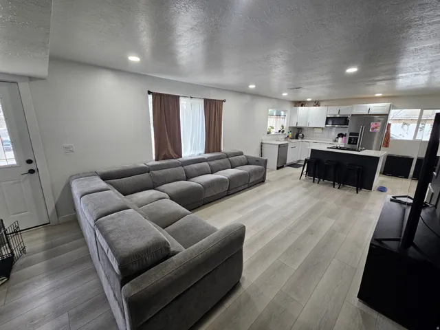 Living area with a textured ceiling, recessed lighting, and light wood-style flooring