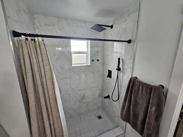 Full bath with a marble finish shower