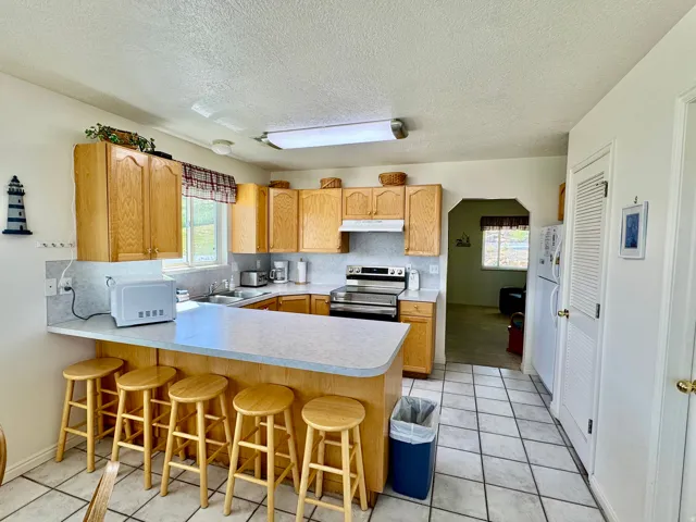 Kitchen with light wood cabinetry, white tile flooring, and a breakfast bar