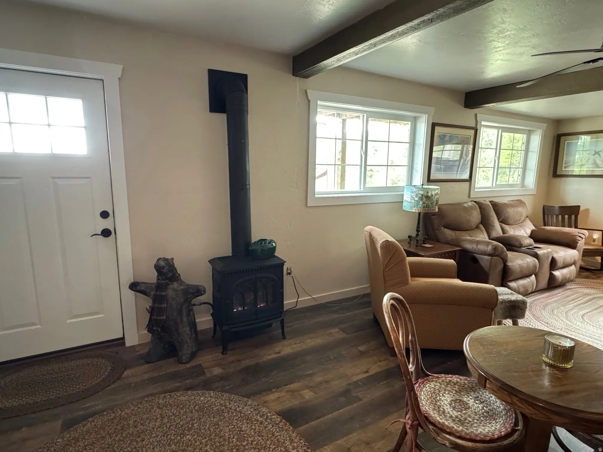 Family Room dark wood finished floors, a wood stove, beam ceiling, and a ceiling fan
