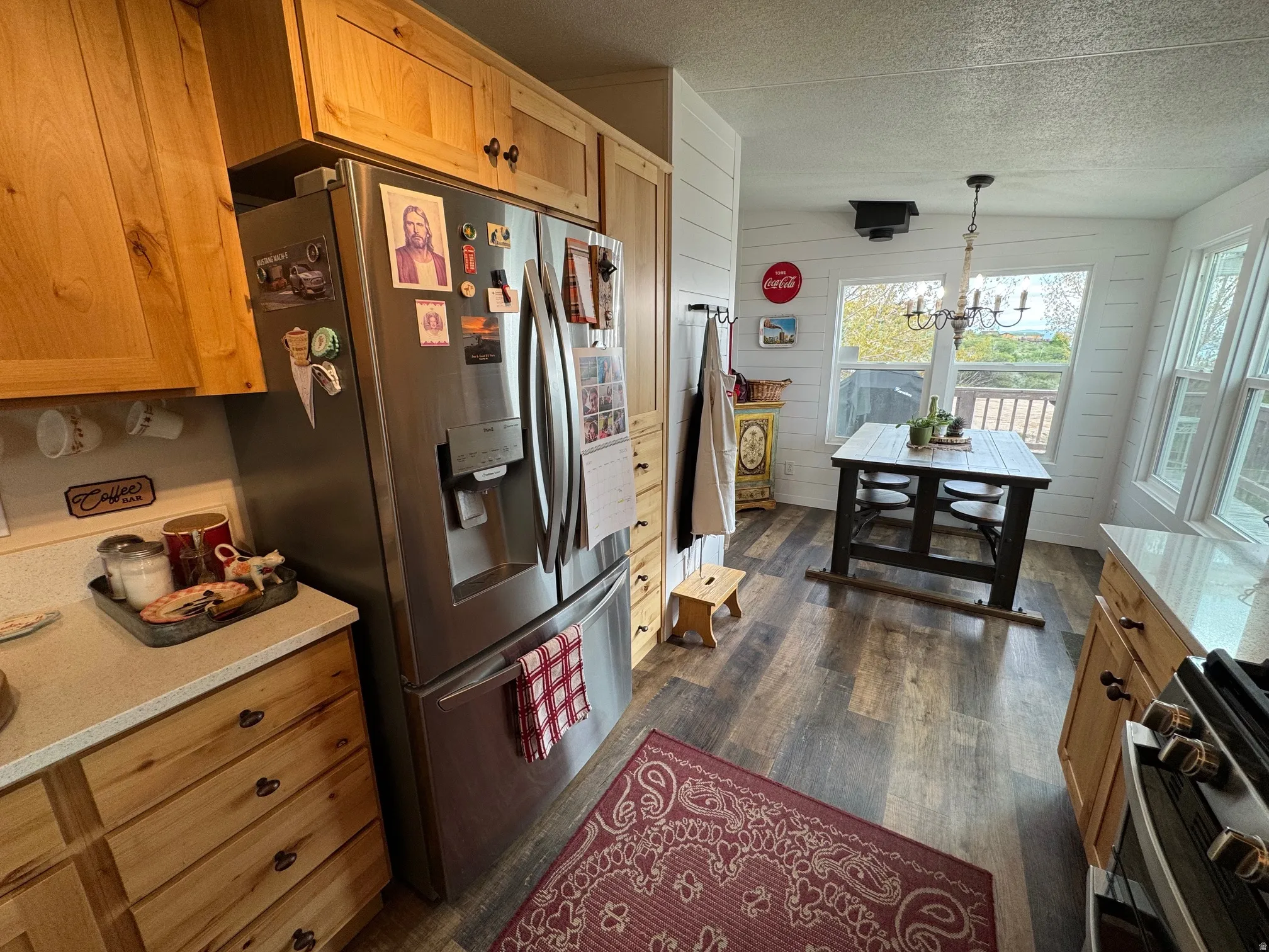 Kitchen featuring LVT flooring, appliances with stainless steel finishes, Quartz countertop, new cabinetsKitchen featuring stainless steel appliances, a textured ceiling, dark wood-type flooring, pendant lighting, and a chandelier