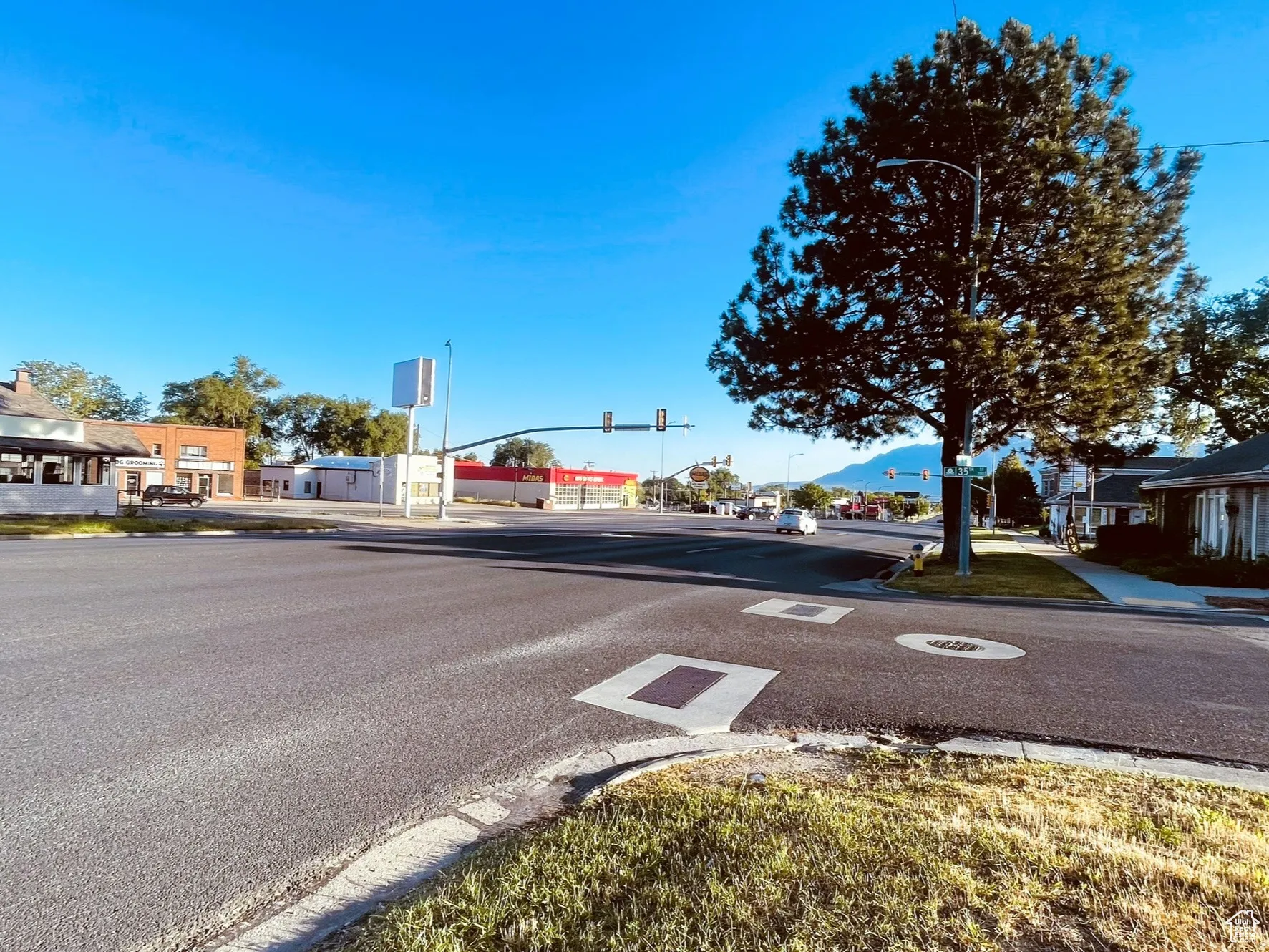 View of asphalt street featuring traffic lights, curbs, sidewalks, and a residential view