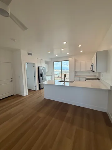 Kitchen with white cabinetry, a peninsula, dark wood-style floors, stainless steel fridge with ice dispenser, and recessed lighting