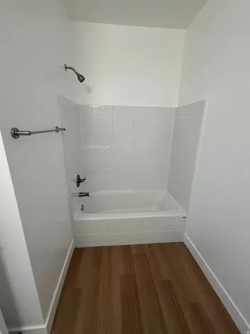 Bathroom with bathtub / shower combination and wood finished floors