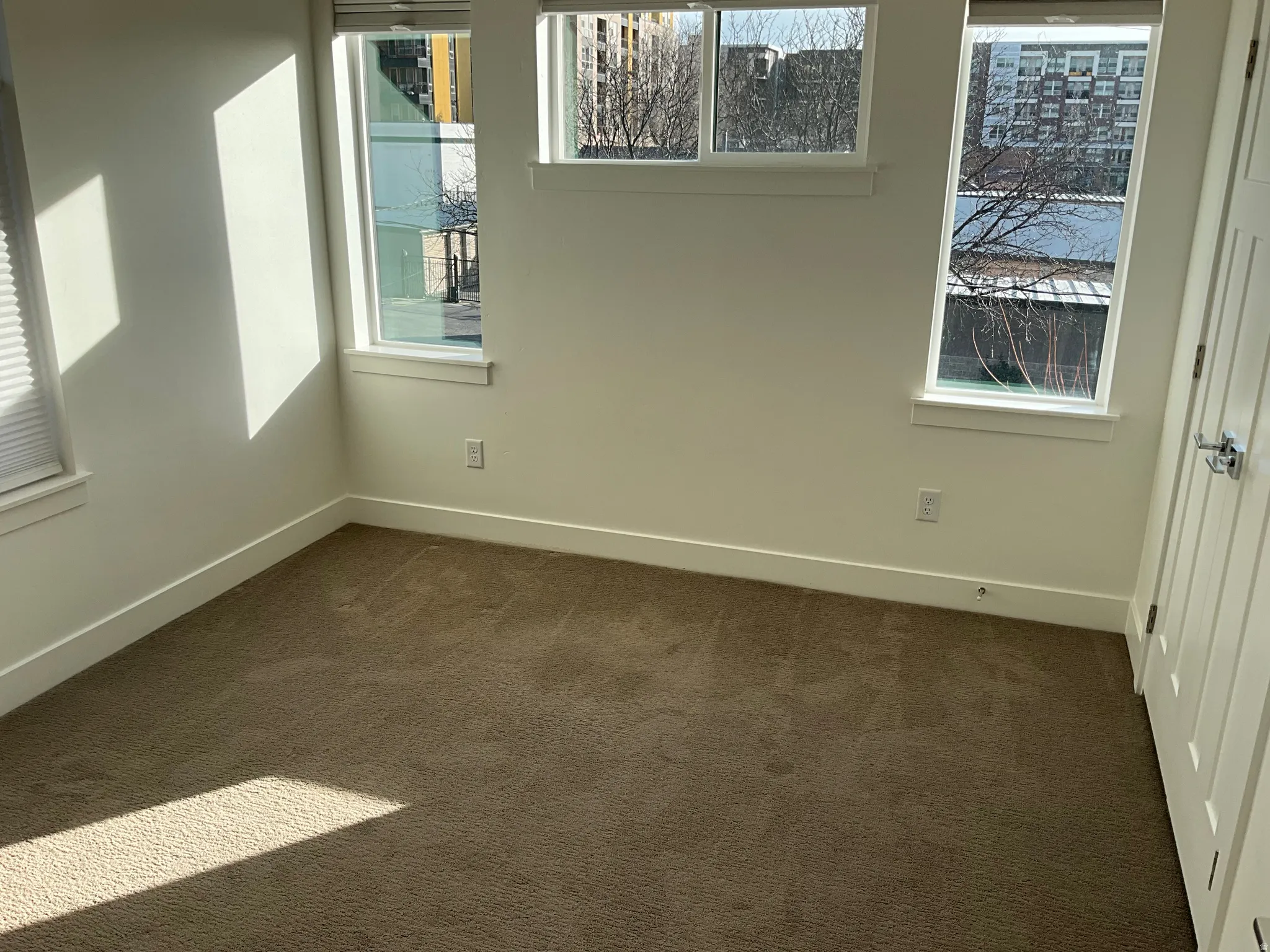 Unfurnished room with dark colored carpet and plenty of natural light