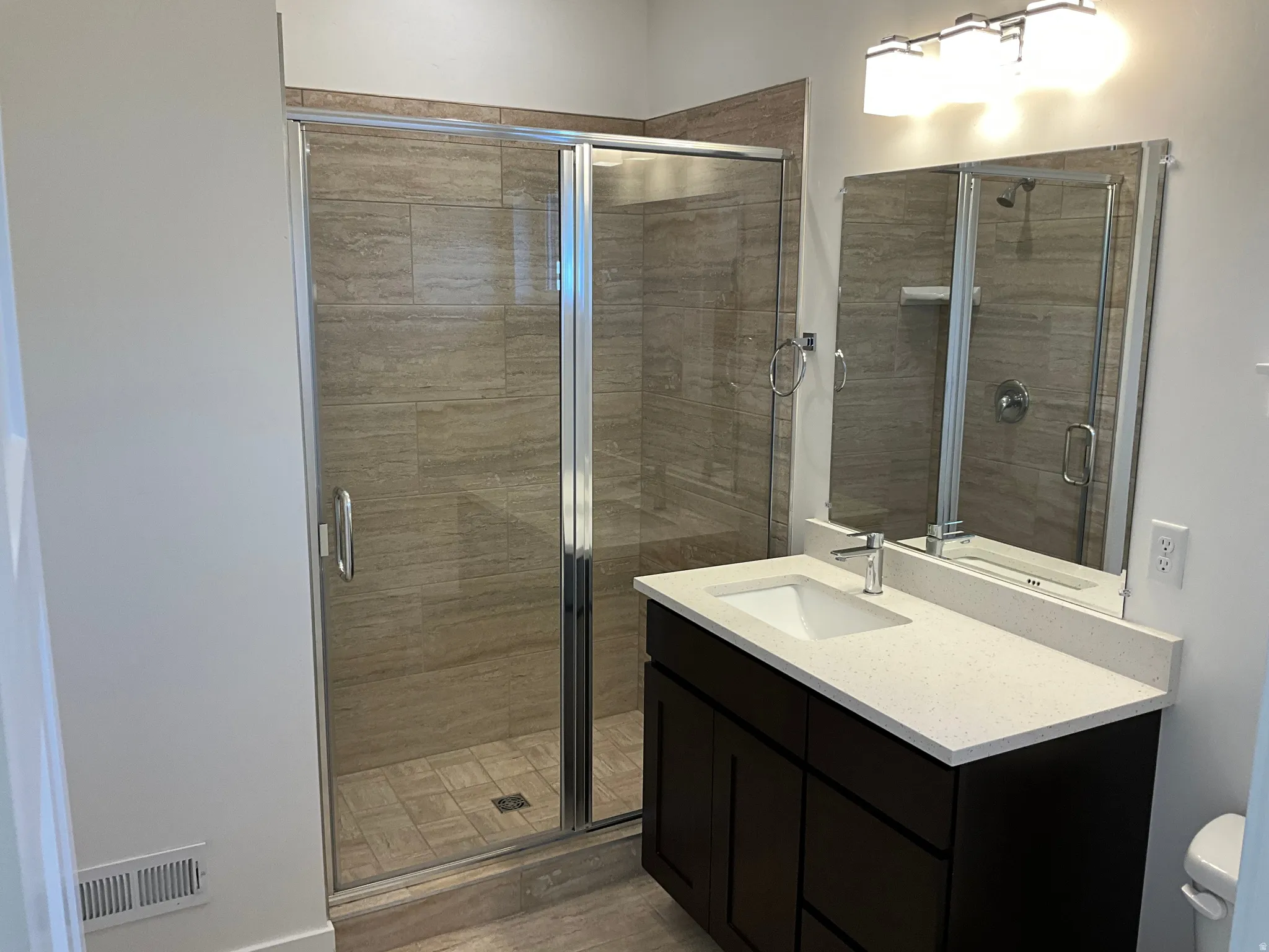 Full bathroom with a stall shower, vanity, and dark wood-style floors