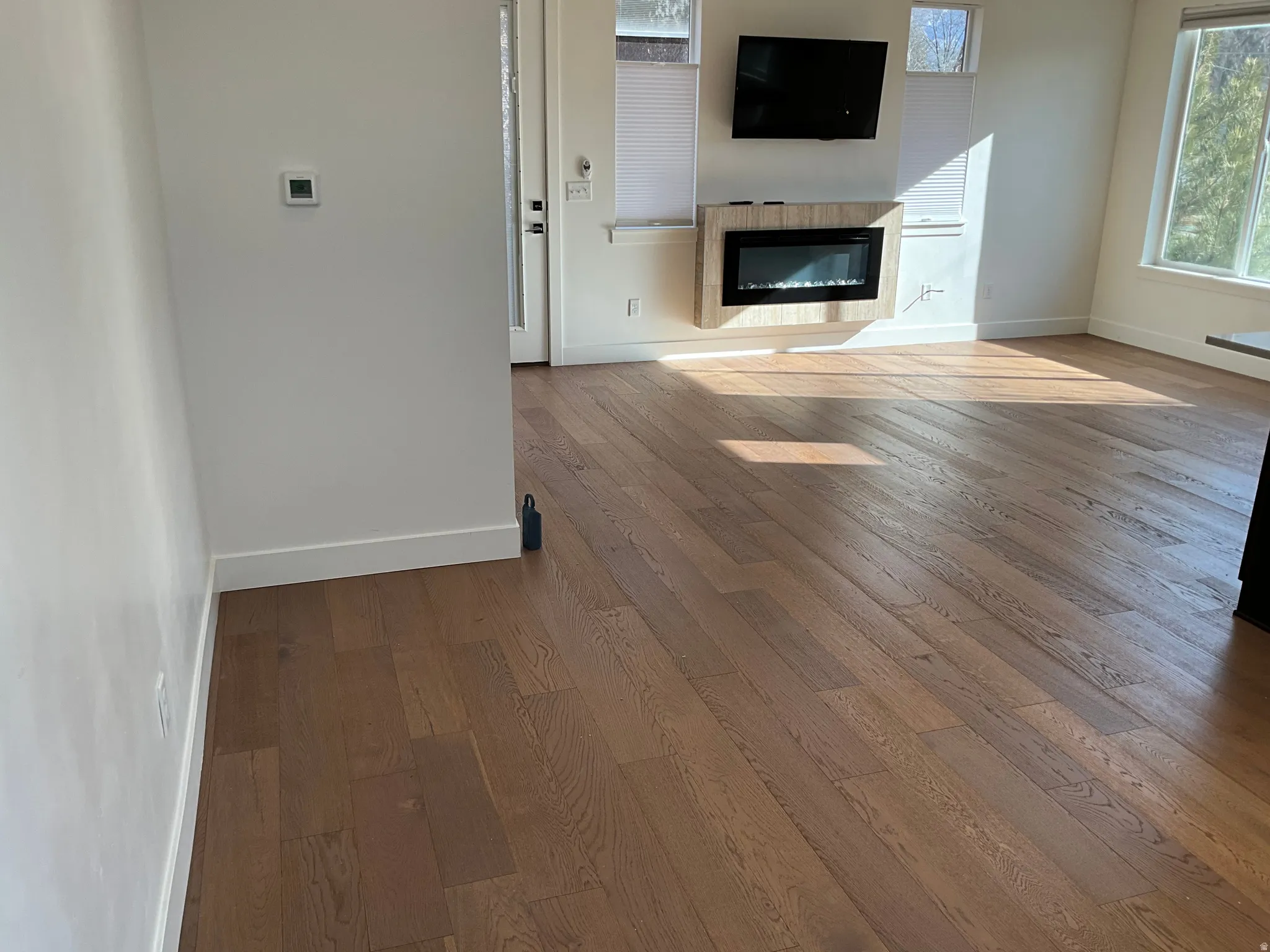 Unfurnished living room featuring hardwood / wood-style flooring and a glass covered fireplace