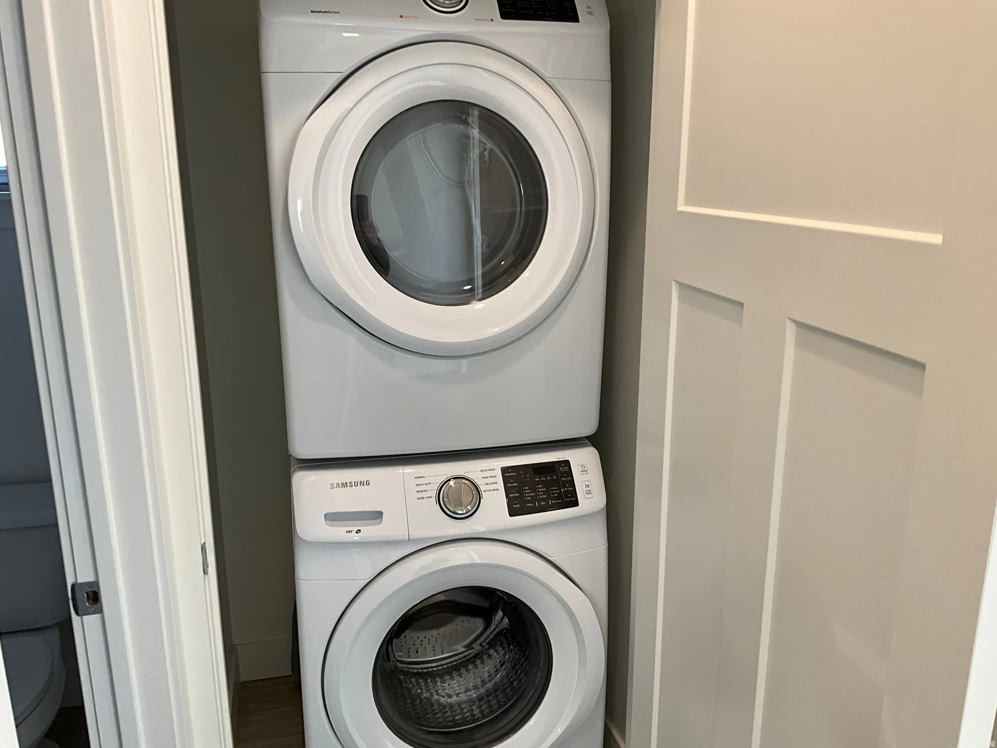 Laundry area featuring stacked washing machine and dryer and wood finished floors