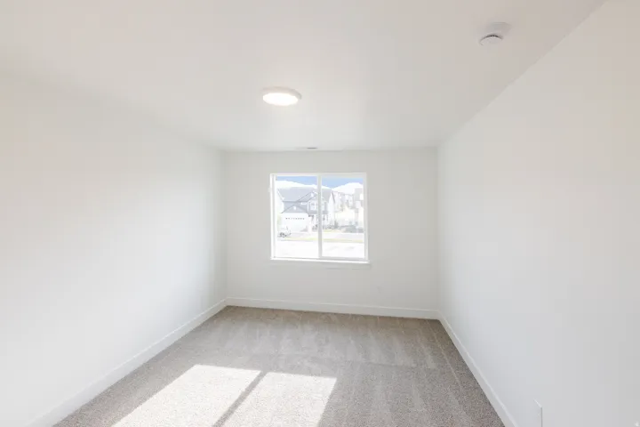 Light-filled room featuring a single window, recessed ceiling light, and neutral-toned carpeting