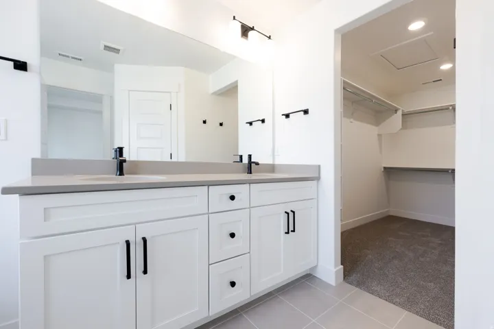 Bathroom featuring a dual vanity with a light gray countertop, undermount sinks, and matte black fixtures