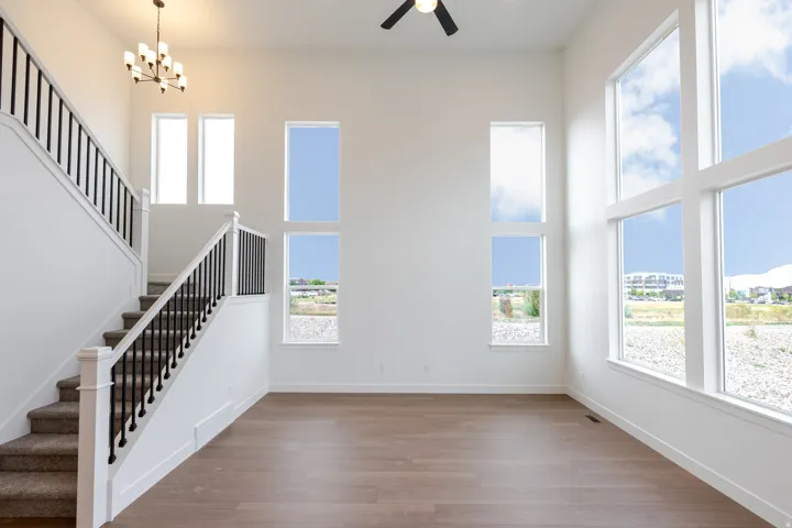 Two-story living area featuring wood-finish flooring, a contemporary chandelier, and a ceiling fan