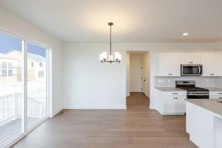 Open-concept dining area featuring wood-finish flooring, a contemporary chandelier, and direct access to an outdoor deck
