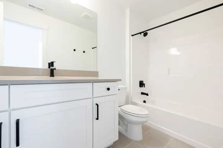 Bathroom featuring a white vanity with matte black hardware, a grey countertop, and an integrated sink with a matte black faucet