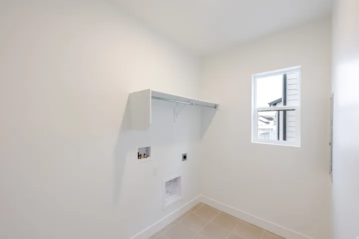 Dedicated laundry area featuring a single window, built-in shelving with hanging rod, and tile flooring