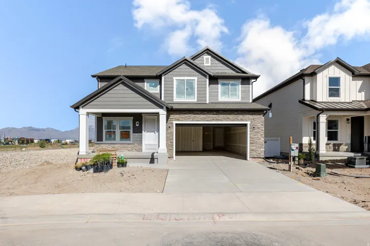 Craftsman inspired home with covered porch, concrete driveway, an attached garage, a mountain view, and stone siding