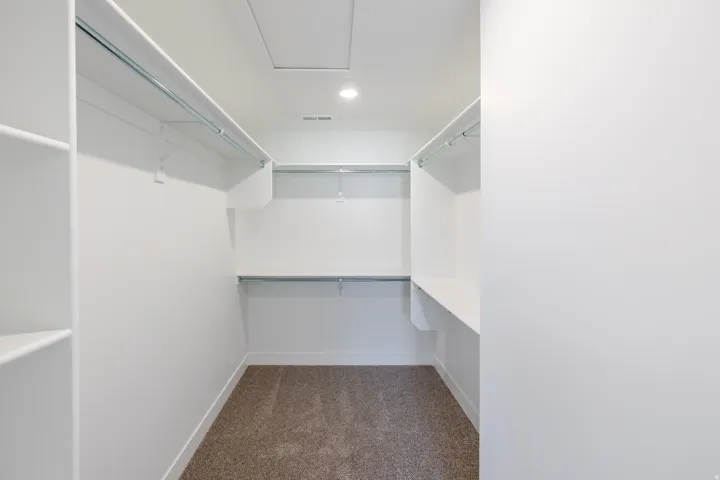 Spacious walk-in closet featuring built-in shelving, multiple hanging rods, and recessed lighting