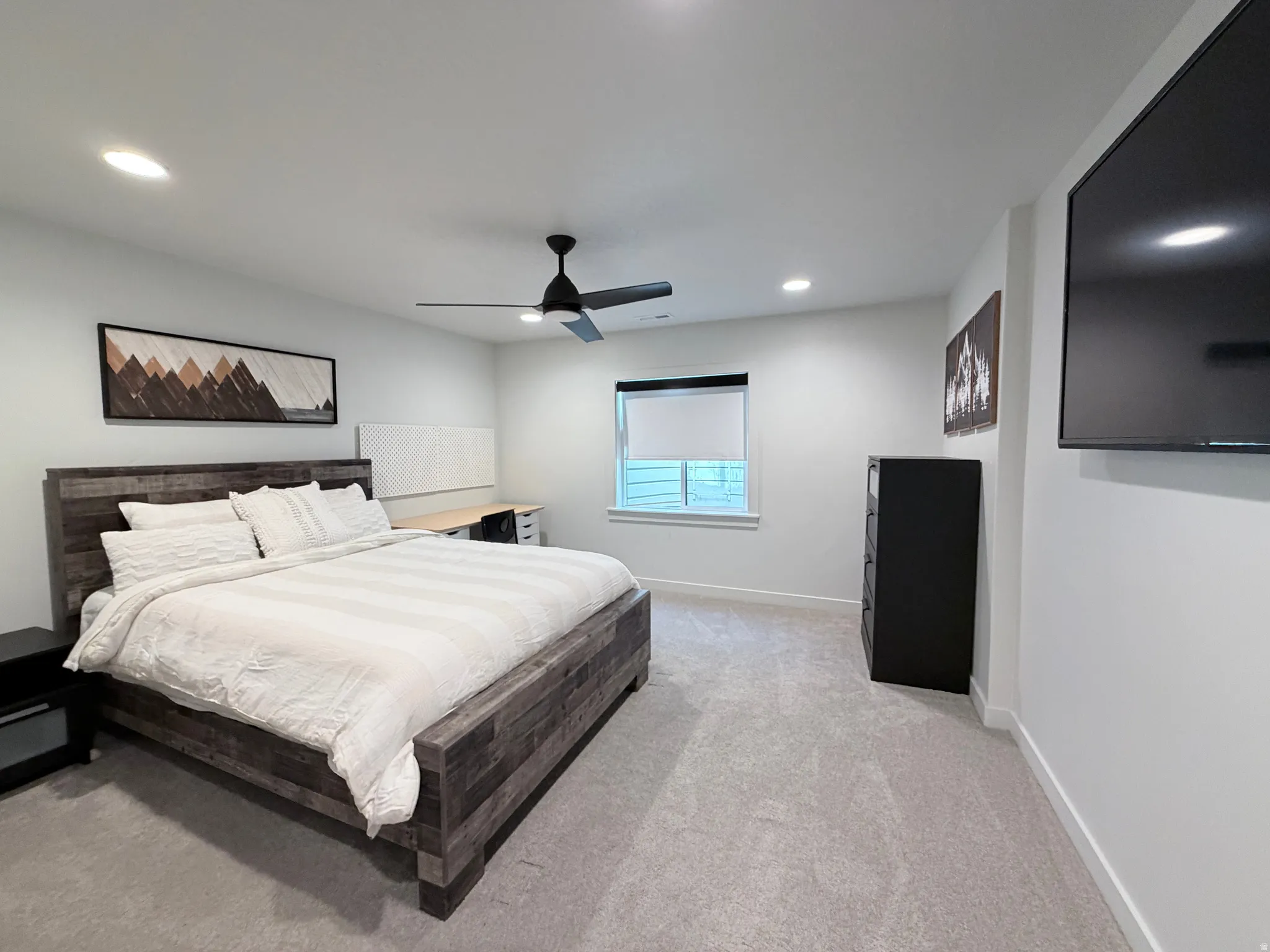 Bedroom featuring light carpet, a ceiling fan, queen bedroom furniture, desk and chair