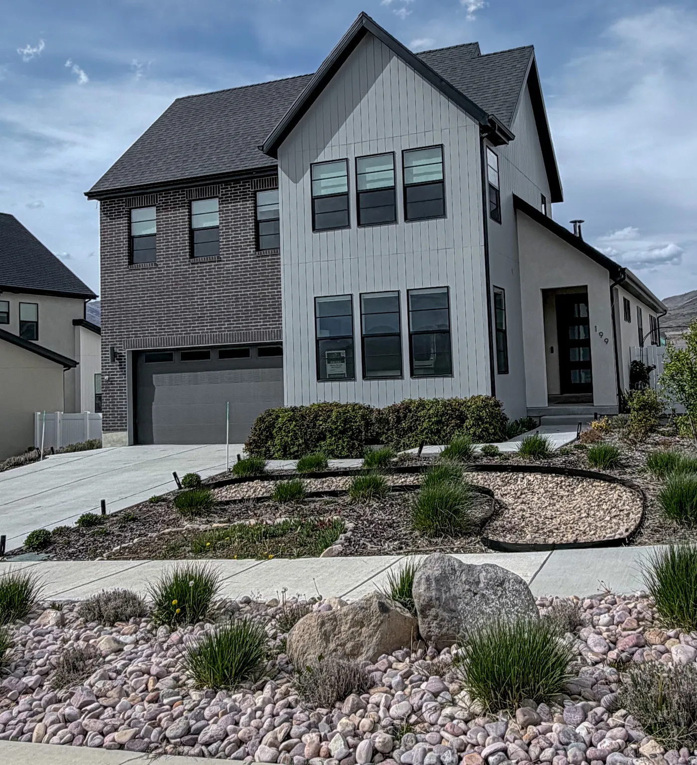 Modern inspired farmhouse with a garage, driveway, and roof with shingles