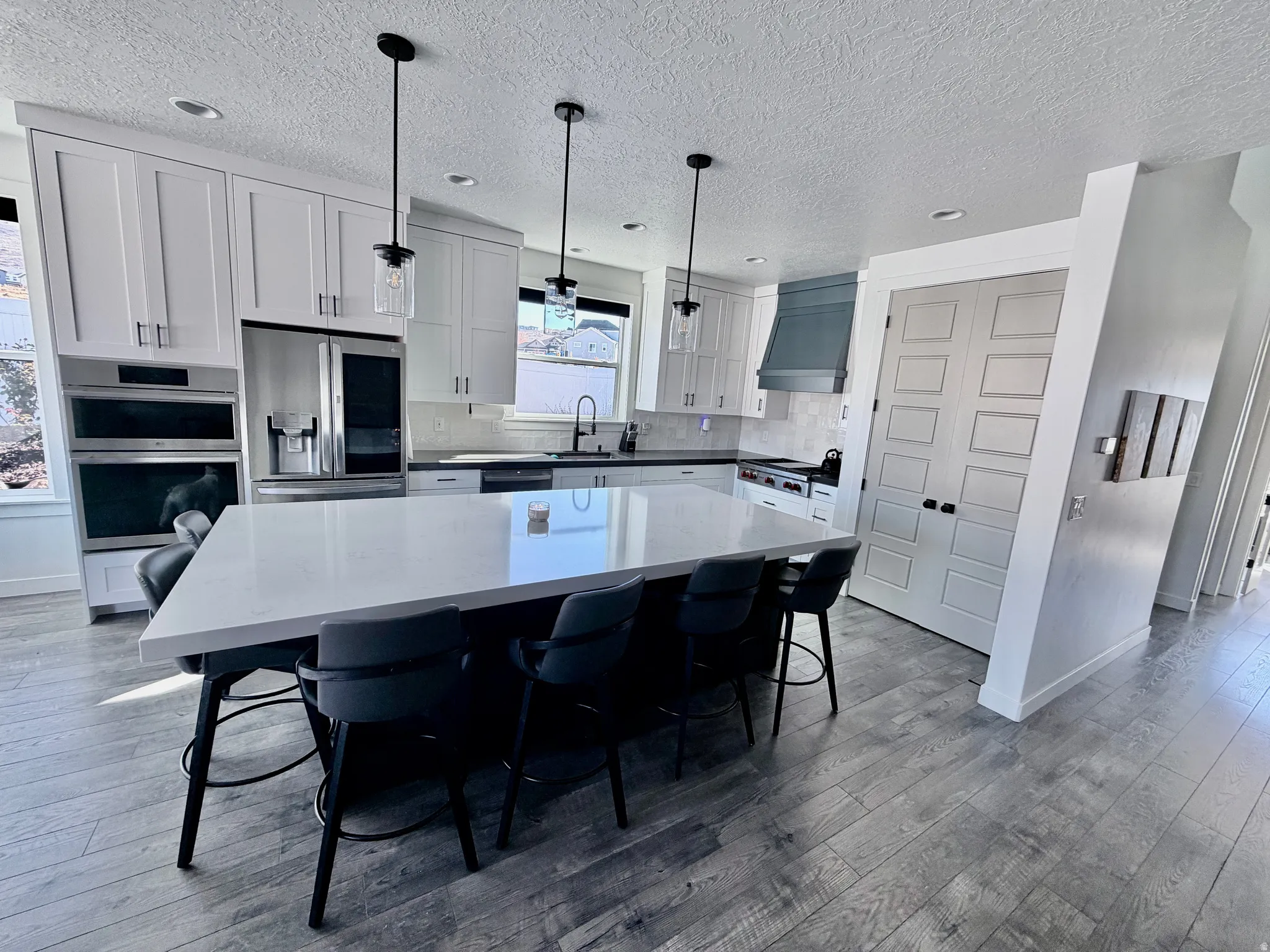 Kitchen featuring a center island, pendant lighting, white cabinets, a breakfast bar area, and LG and Wolf appliances with stainless steel finishes
